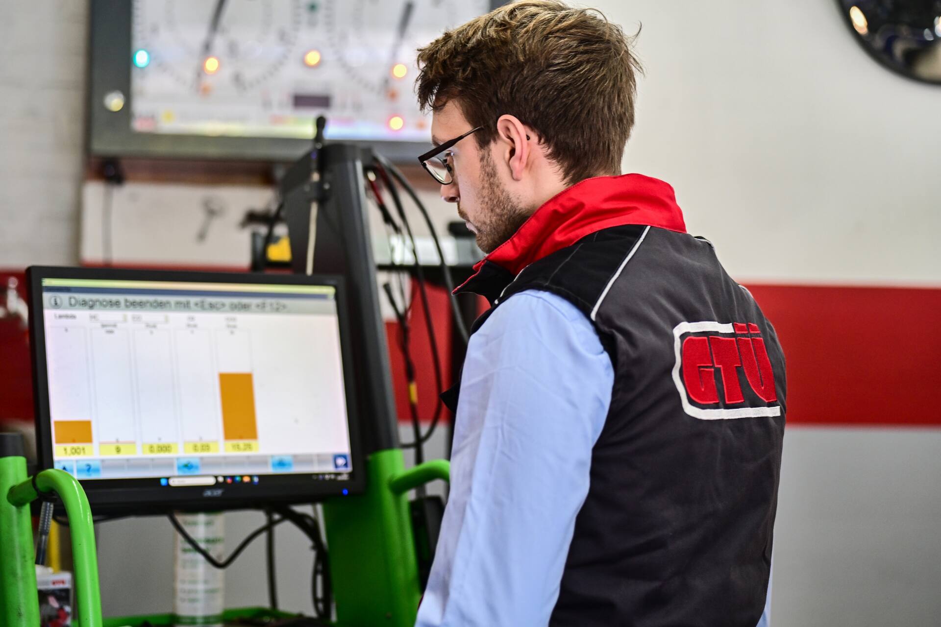 Kfz-Mechatroniker prüft Fahrzeugdiagnose am Computer in der Autowerkstatt.